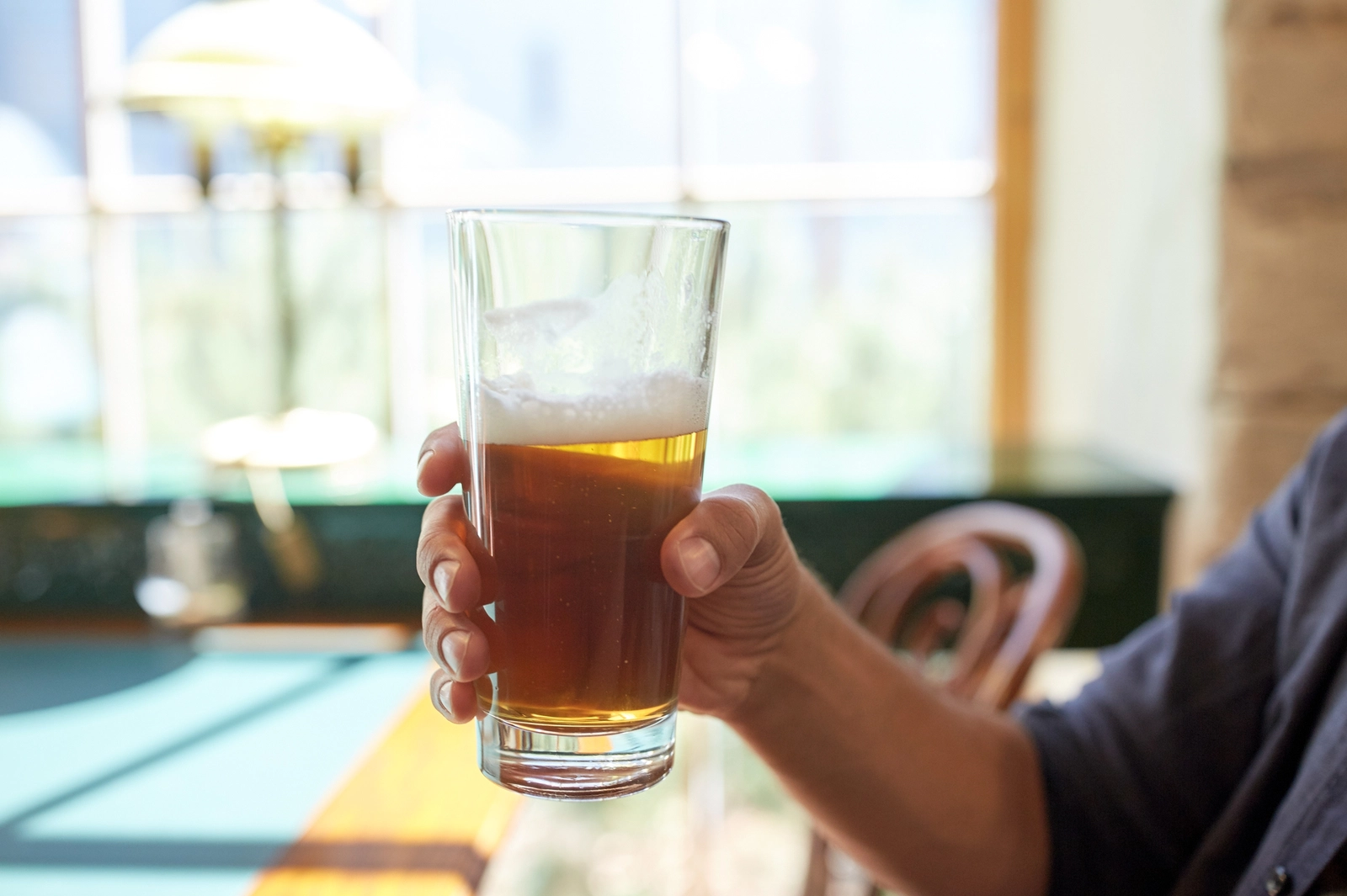 Blood in stool after drinking: A hand holding a glass of beer.